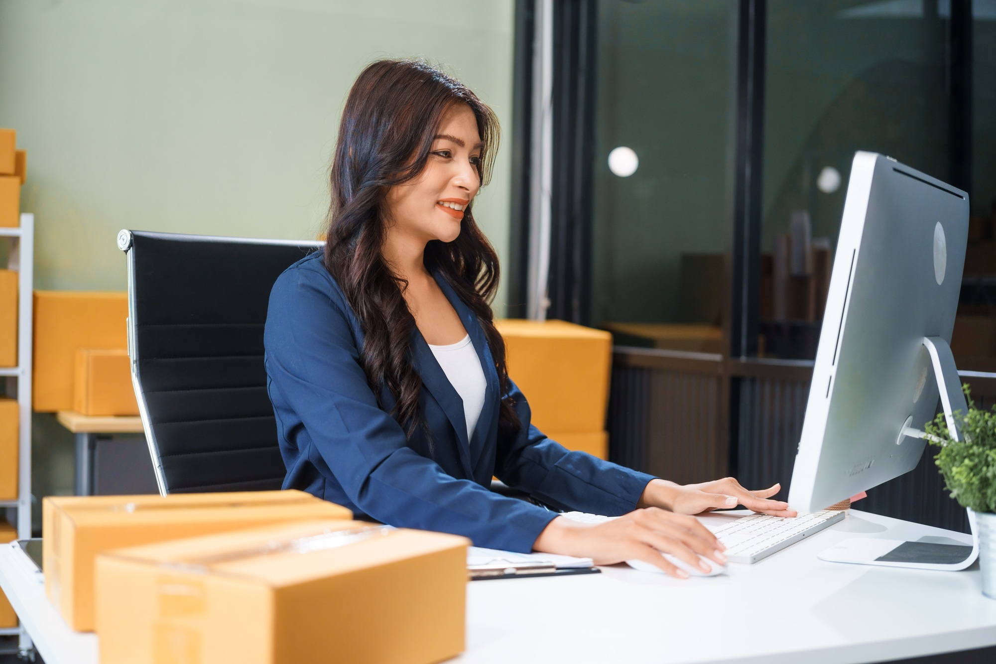 A young Asian businesswoman sits at her table, watching computer screen.She analyzes, plans, sells